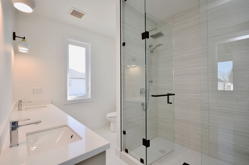 Ensuite bathroom with double sink vanity and large glass enclosed shower stall.